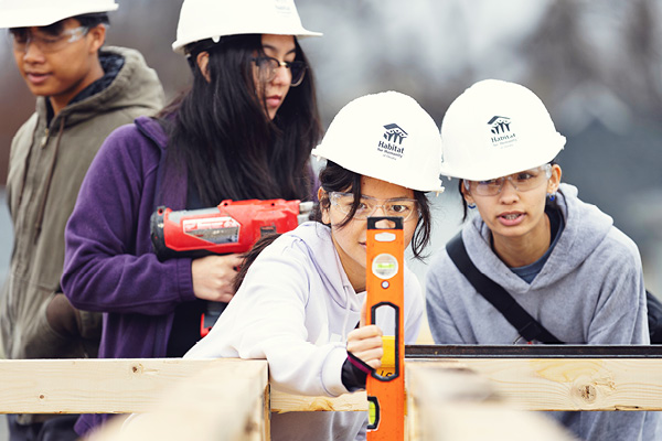 Students work together on a volunteer project wearing safety gear.