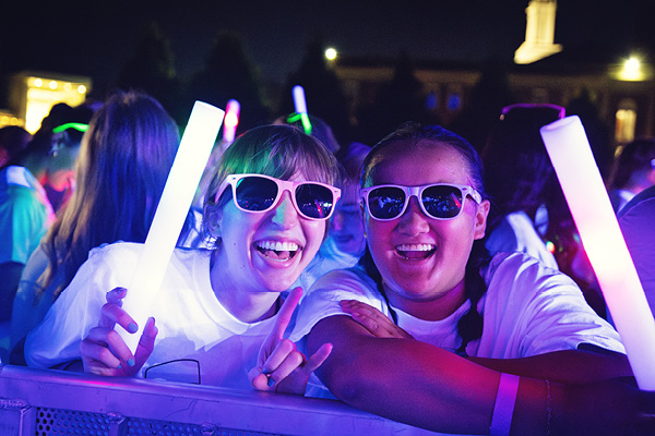 Students attend a nighttime campus event with glow sticks.