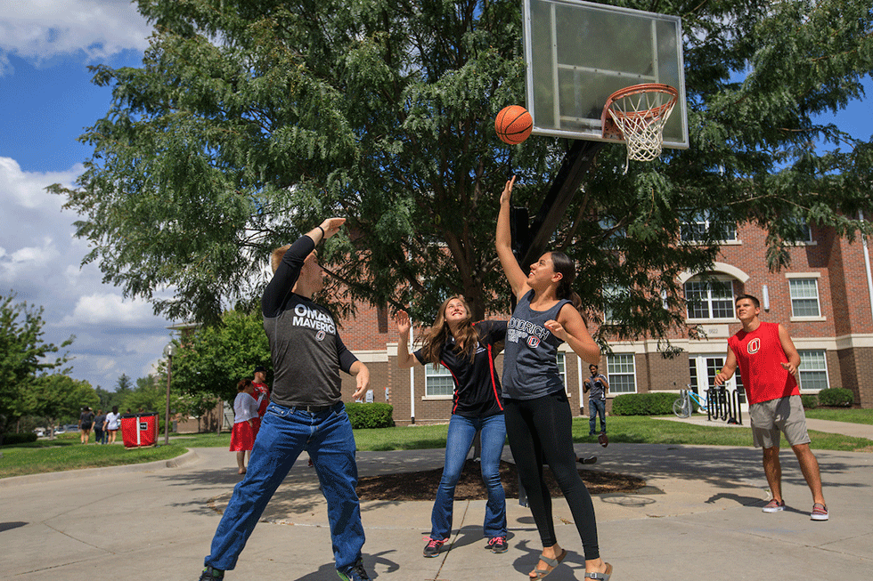 a group of male students playing basketball outside.