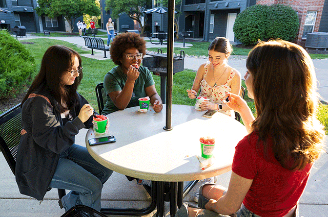 students sitting at a table outside smiling and laughing.