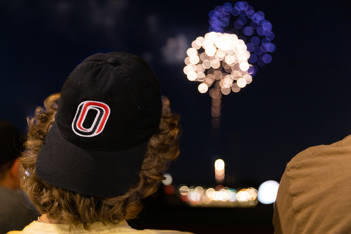 A student wearing a black UNO baseball cap watching fireworks