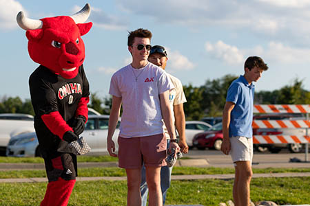 Delta Chi members playing cornhole with the UNO mascot Durango during Mav Fest