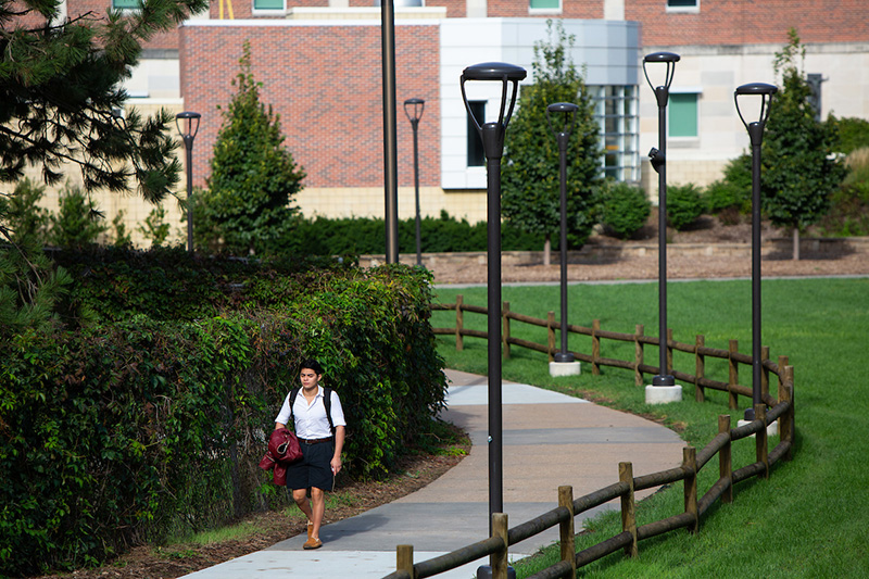 Student walking on campus sidewalk