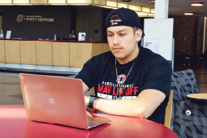 Male student sitting at table working on laptop