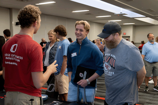 a young male stduent and his dad talk to a uno ambassador at be a mav day.