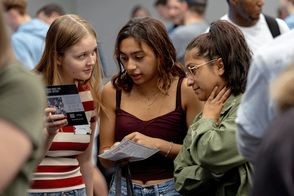 two female high school students and a mom stand together at jr be a mav day at UNO.