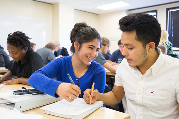 a female student helps a male student solve a problem in math class