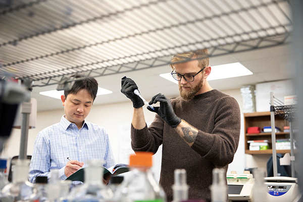 an assistant professor of biology works with recent graduate in his lab in Allwine Hall at the University of Nebraska at Omaha in Omaha, Nebraska