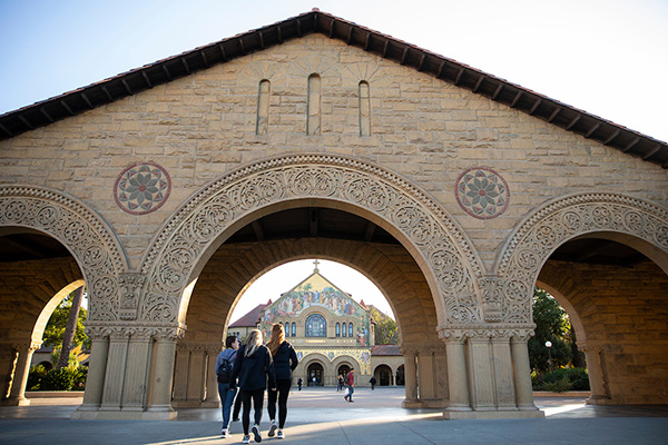 uno students walk under an archway on stanford university campus