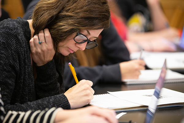a student writes with a pencil in a notebook