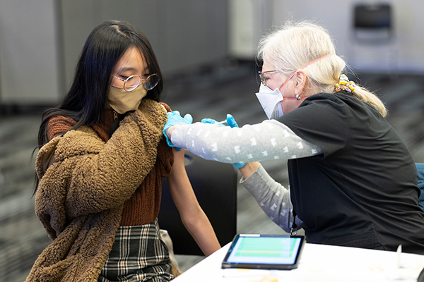 a nurse gives a young woman a vaccination at a public health event