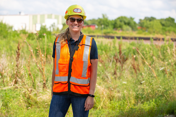 a woman in construction gear smiles
