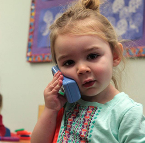 UNO Child Care Center student pretending to talk to someone on the phone