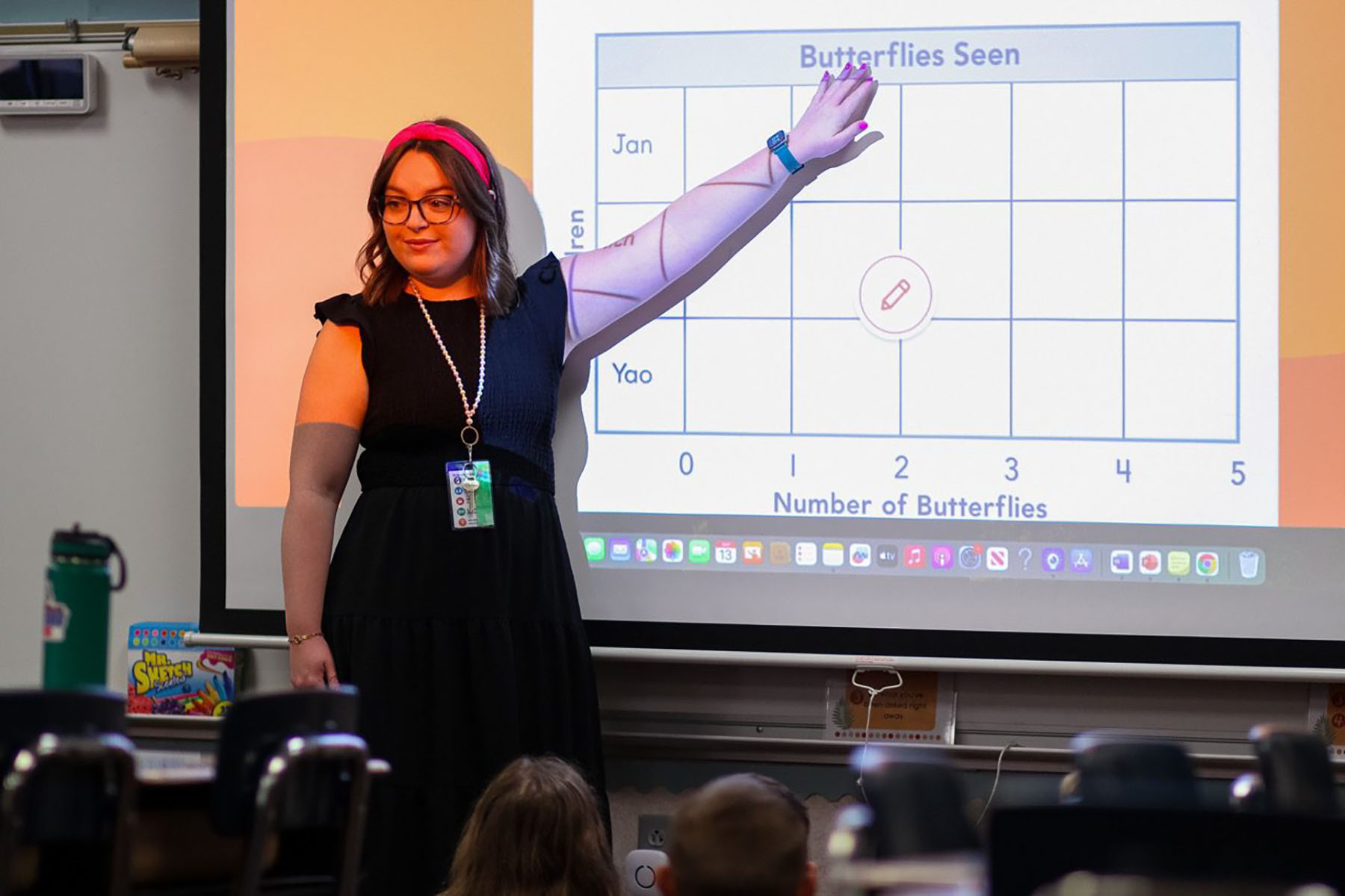 A teacher stands in a classroom conducting a lesson