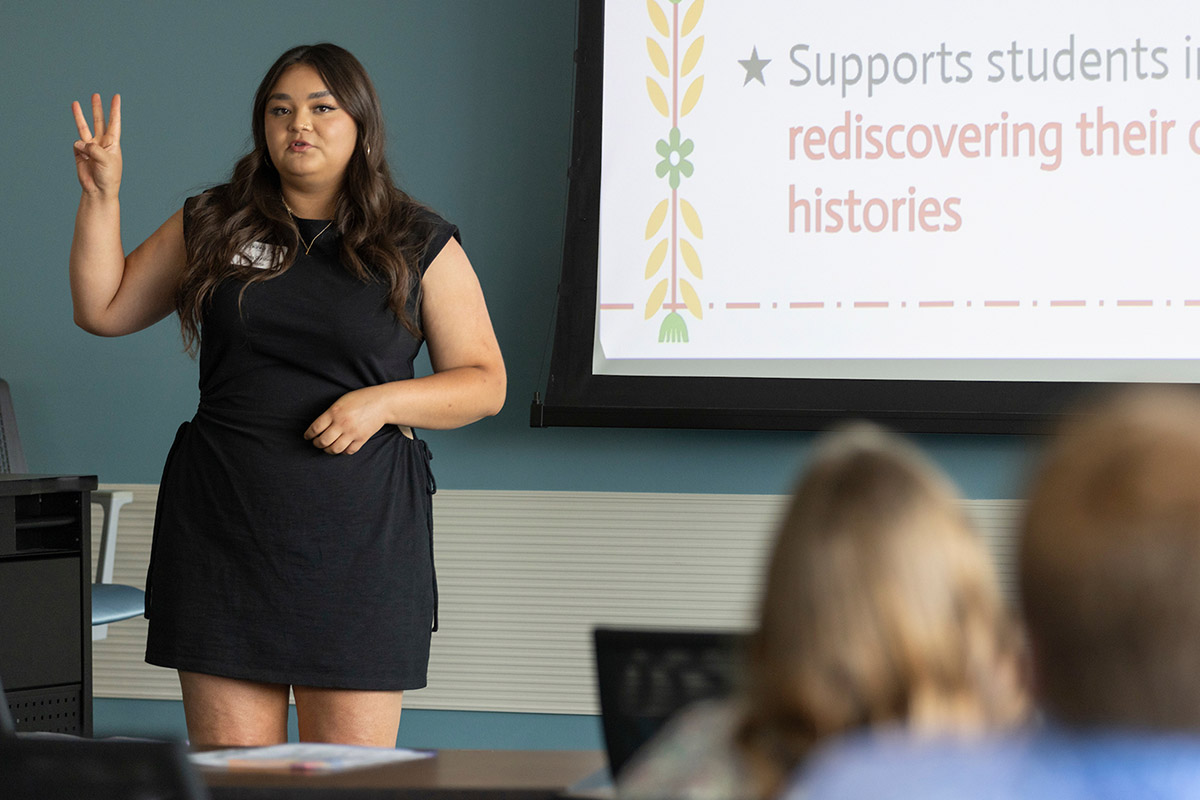 A person stands at the front of a classroom and gives a presentation