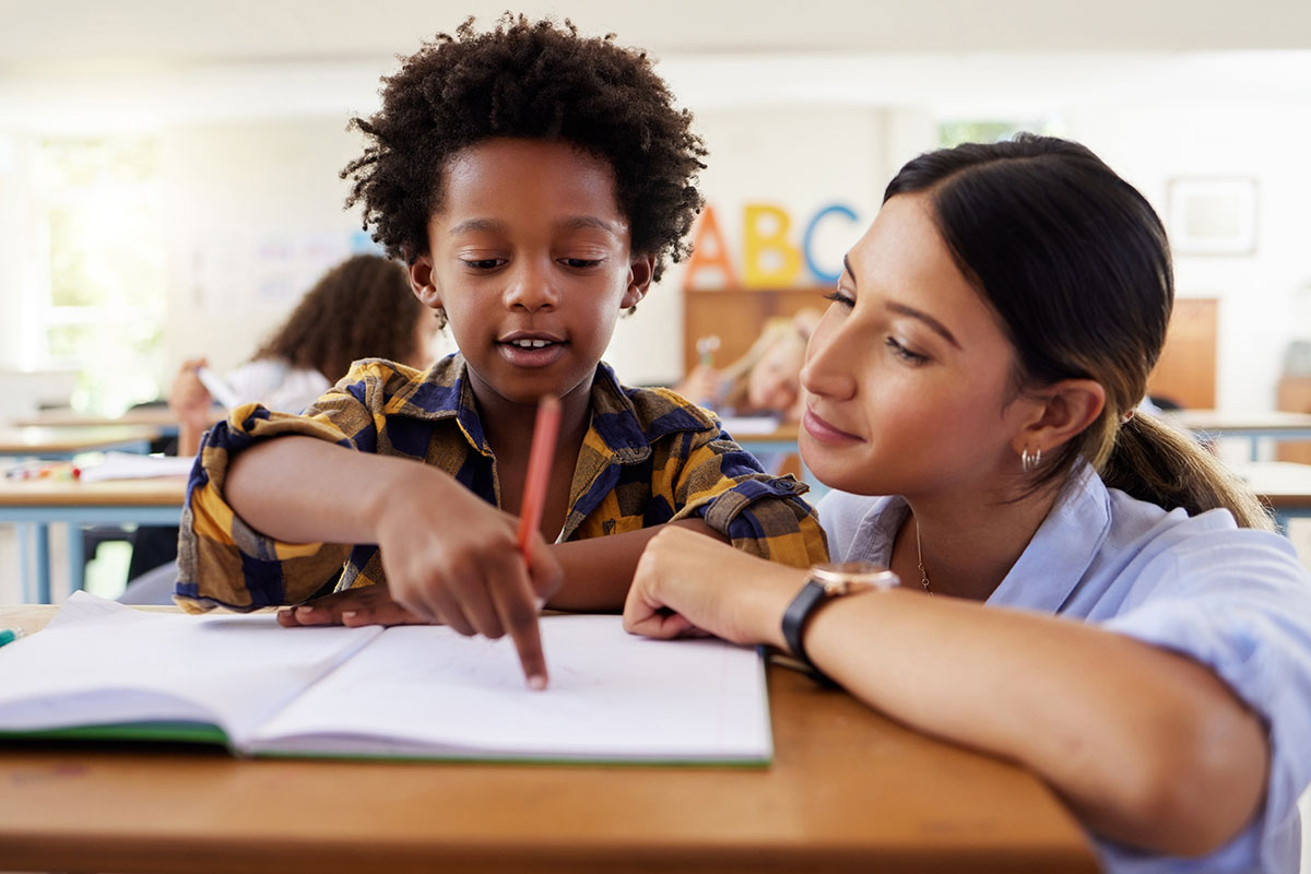 A teacher helps a young student in a classroom