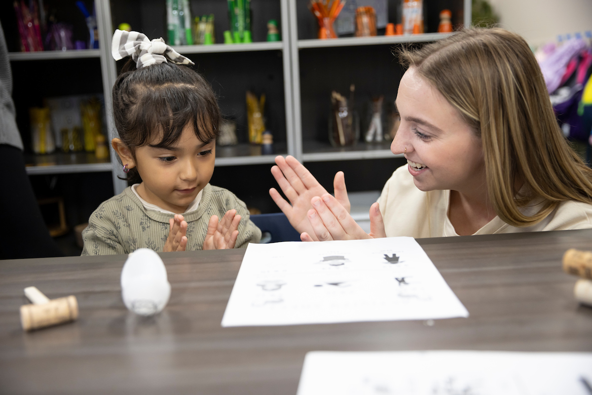 An aspiring educator works with a small child in a preschool