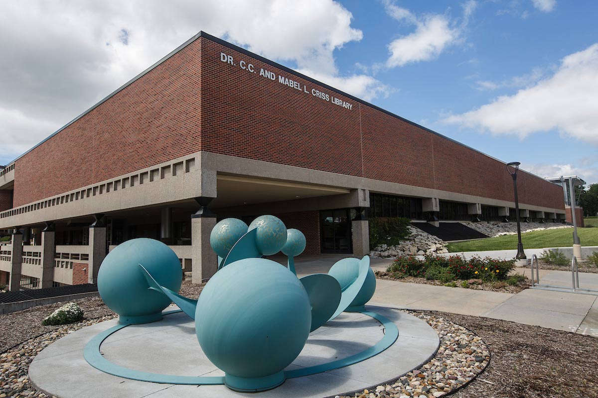 a photo of the criss library building. in the foreground there is a blue, spherical scuplture.