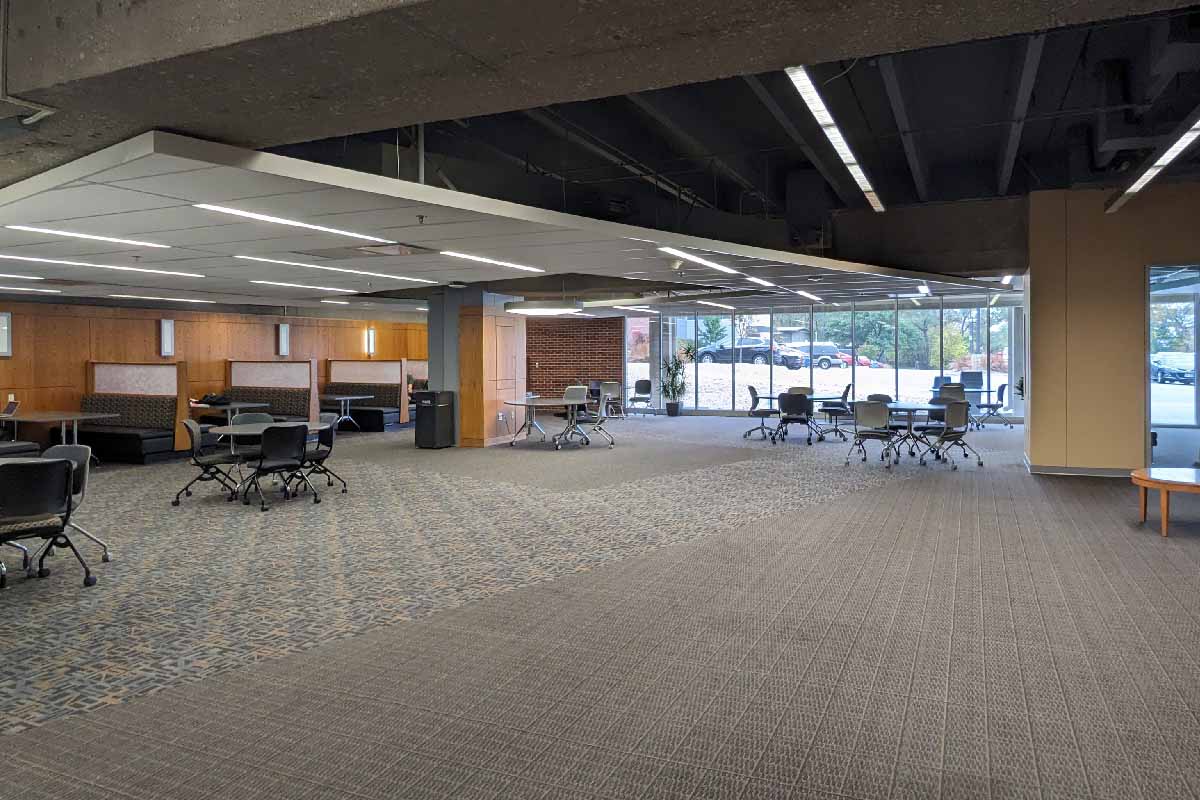 an open study area with booths, tables and chairs, and large windows