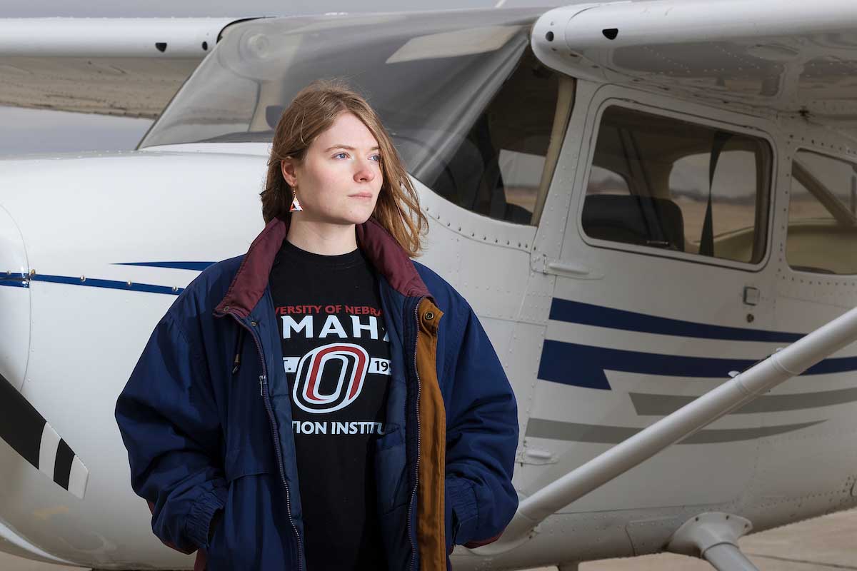 UNO student Gwendoline Dunlop stands in front of a plane after taking a solo flight.