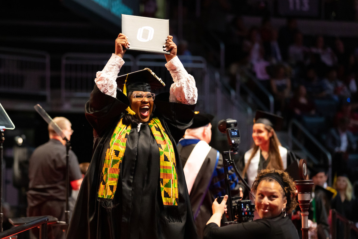 A student raising her diploma in the air after crossing the stage