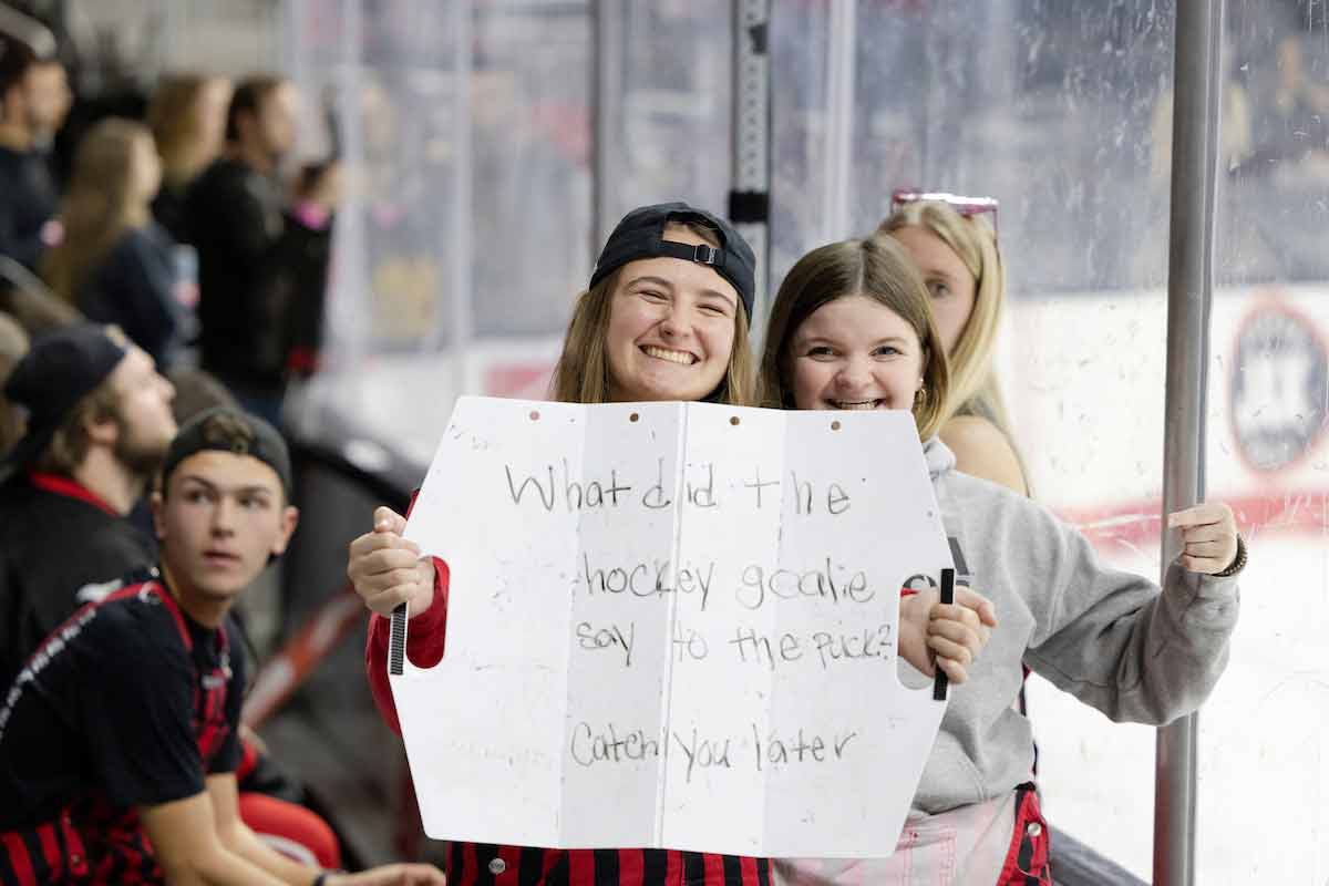 Students hold up a sign as they cheer on the UNO hockey team.
