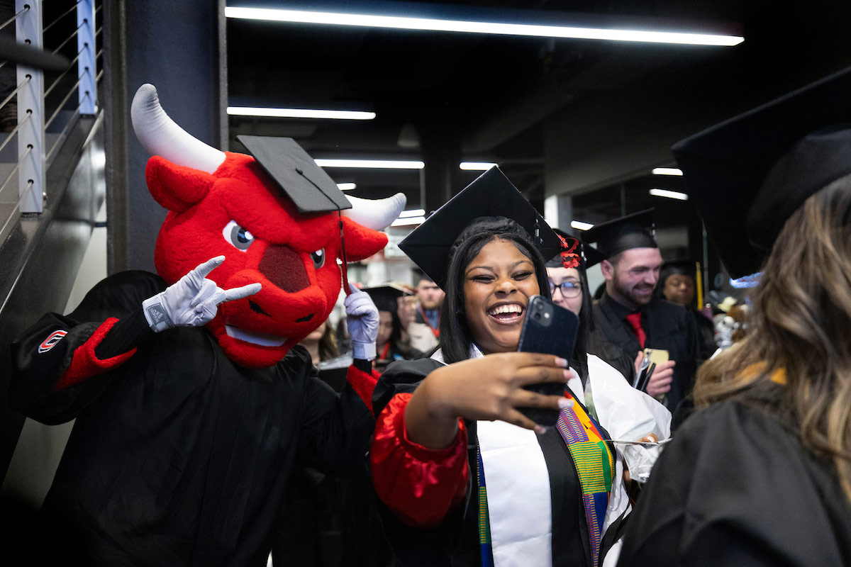 a student takes a selfie with Durango after the ceremony