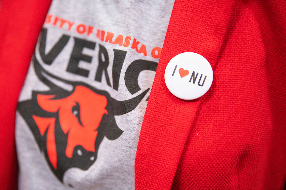student wearing University of Nebraska at Omaha shirt and I Love NU button