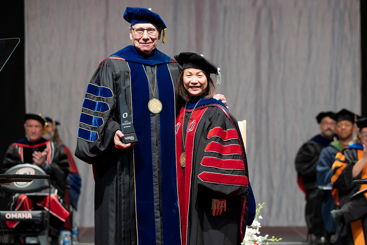 Chancellor Emeritus John E. Christensen (left) receives the Order of the Tower award from UNO Chancellor Joanne Li, Ph.D., CFA (right), during UNO’s December 2023 Commencement Ceremonies. Photo: UNO Office of Strategic Marketing and Communications
