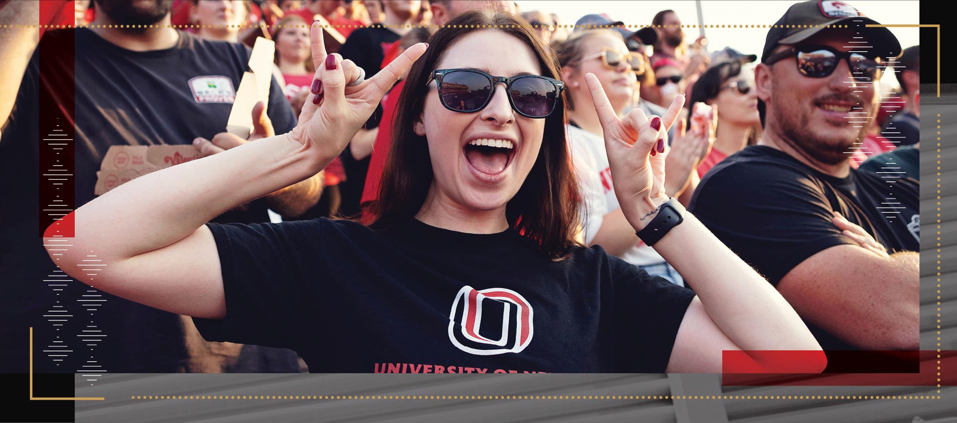 Uno student at event holding both hands up in "Maverick" symbol